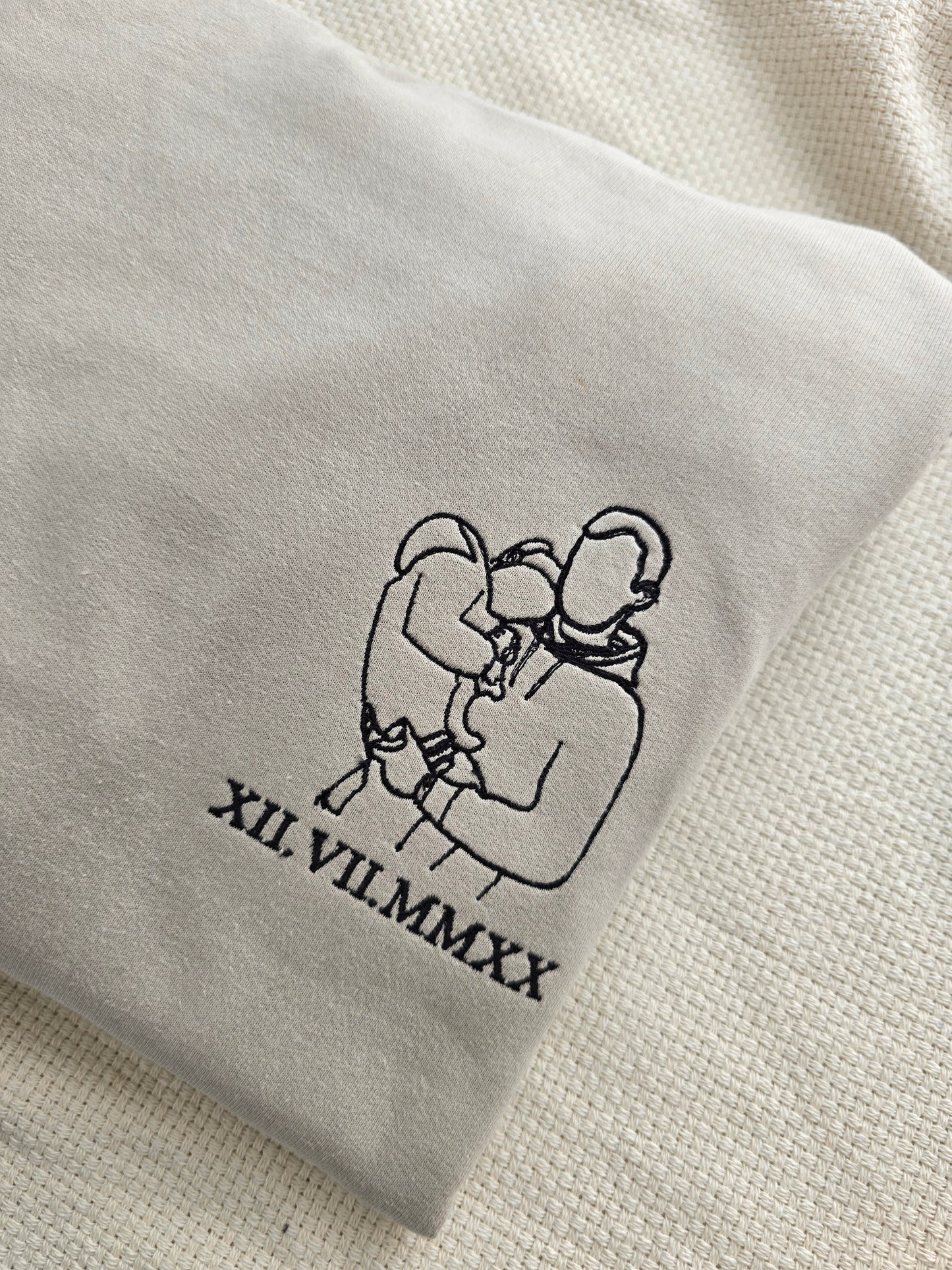 A personalised grey sweatshirt with an embroidered graphic and text on the front.