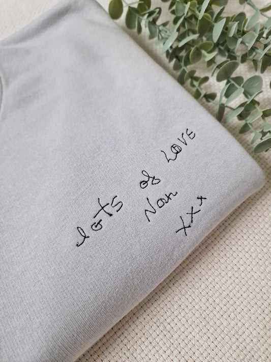 A grey personalised sweatshirt with text and a small photo embroidered on the front.