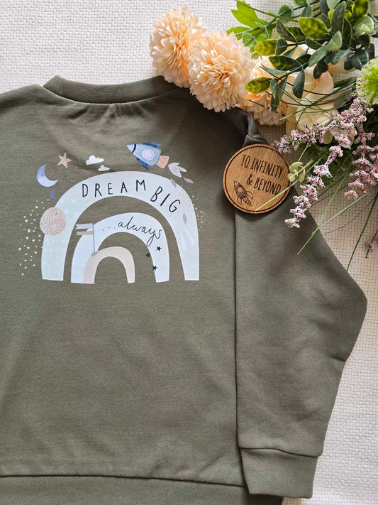 A green mini sweatshirt/hoodie for kids with text 'DREAM BIG' printed on the back, displayed alongside spots and a brand tag.