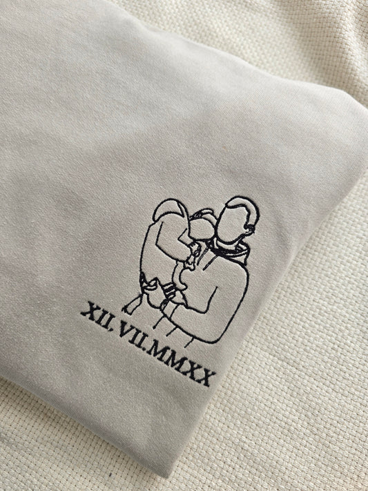 A personalised grey sweatshirt with an embroidered graphic and text on the front.
